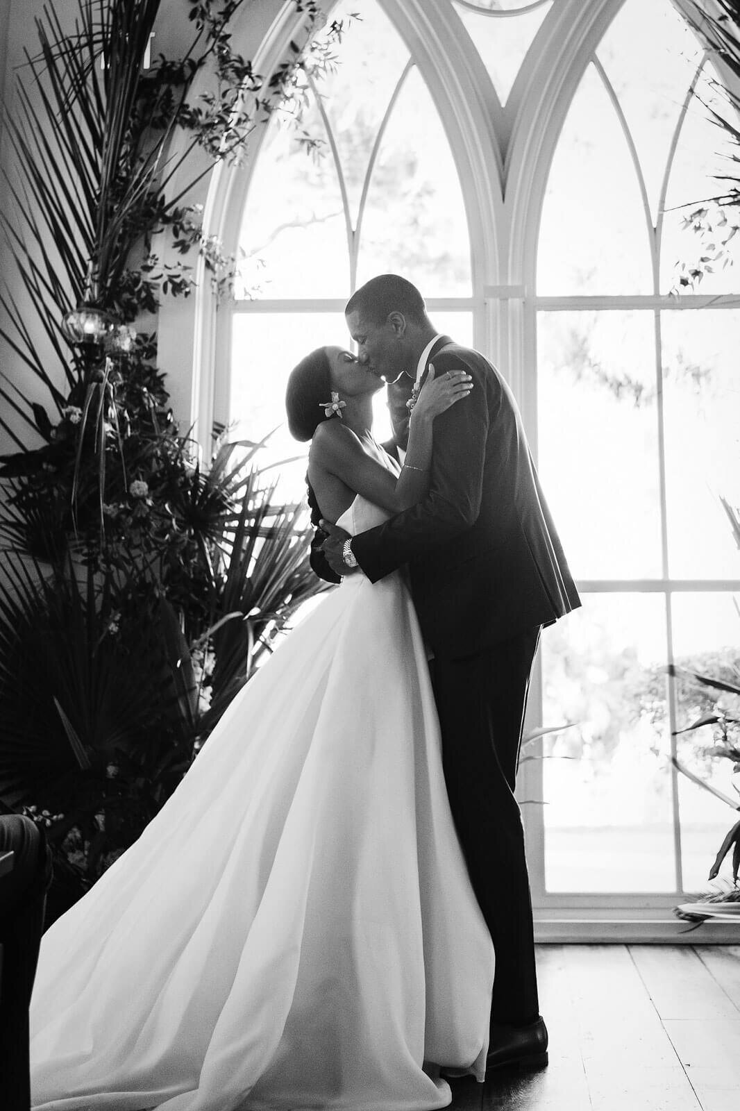 The bride and groom are kissing at the chapel altar in Montage at Palmetto Bluff. Destination wedding image by Jenny Fu Studio