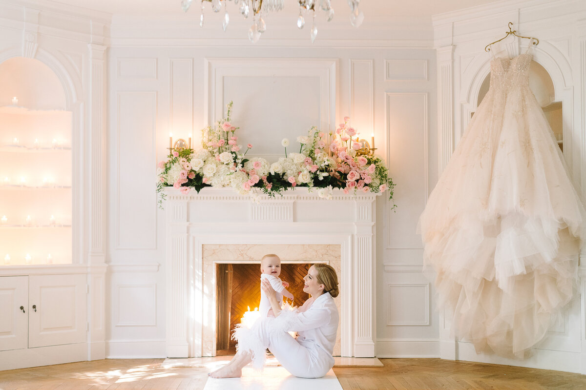 Bride and her infant son beside her gorgeous wedding gown on the morning of her wedding