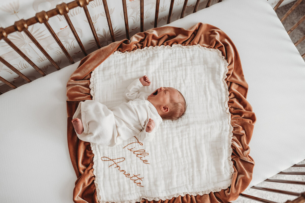 overhead view of baby yawning in crib by Denver newborn photographer, Alyssum Hutchison