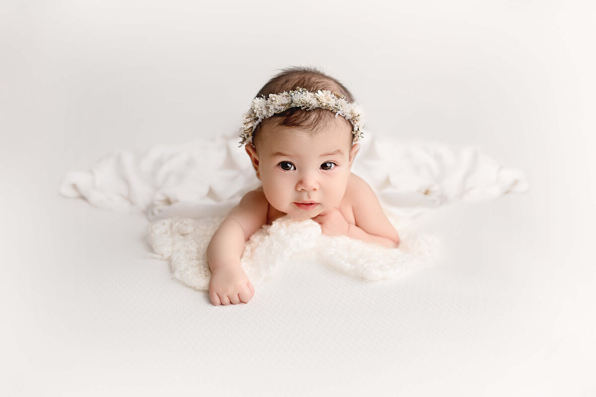 3 month baby poses on white backdrop in niagara