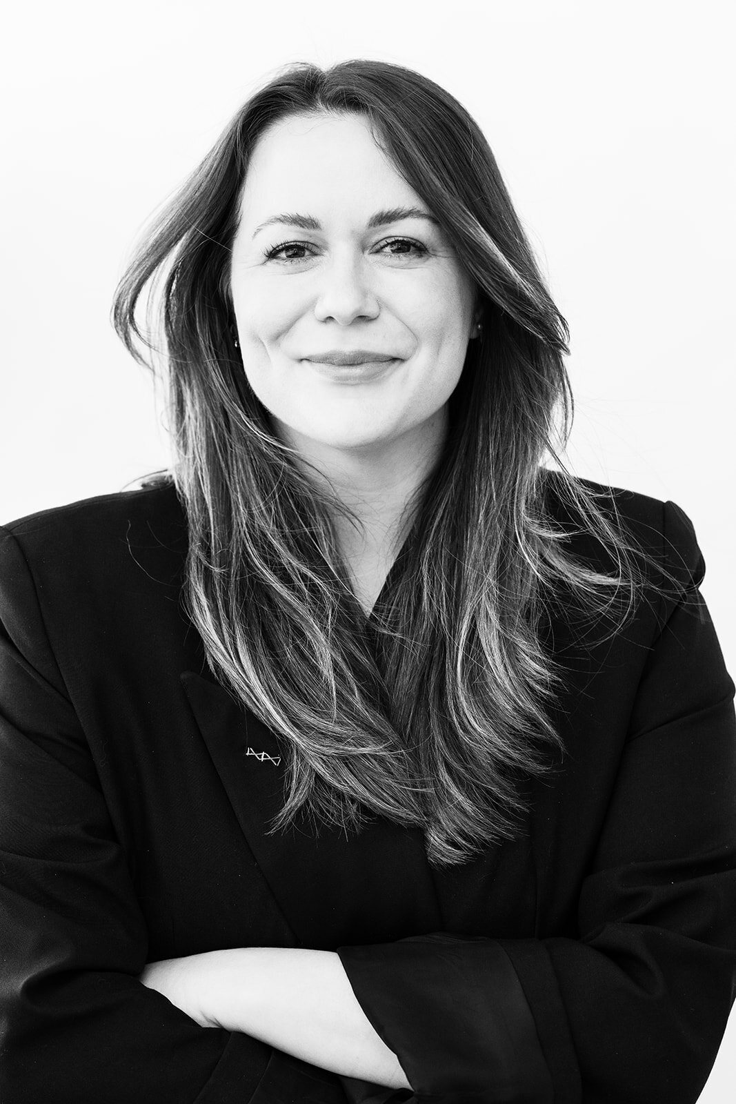 Black and white portrait of a woman smiling with long hair and a dark jacket