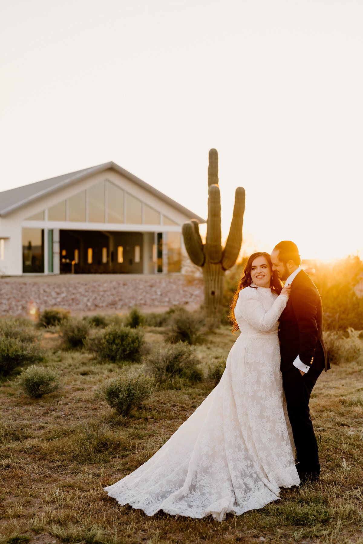 Bride and groom posing in front of a cactus during sunset