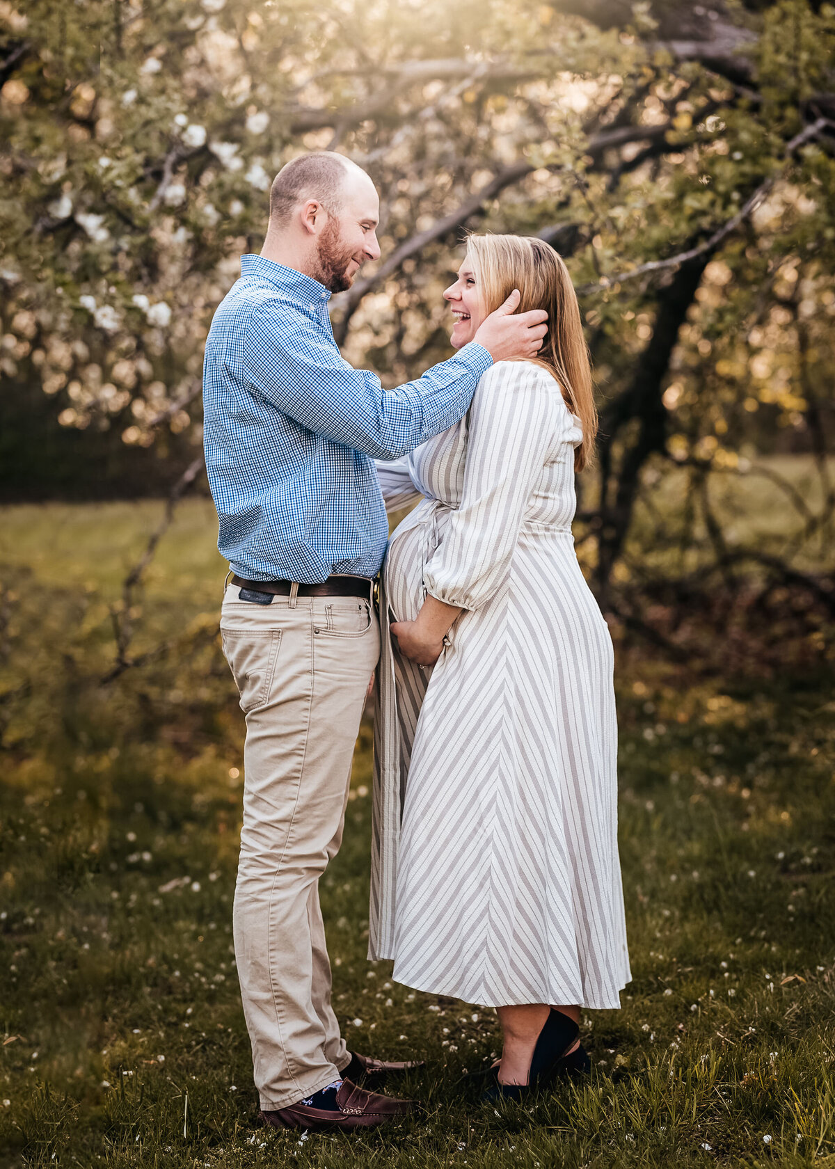 Husband and wife laughing as they face each other in spring maternity session at Carey Cottage in Portsmouth NH by Lisa Smith Photography