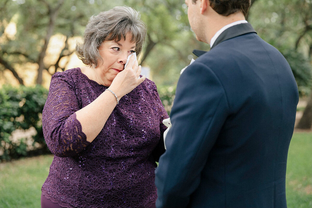 Mother of groom crying in purple dress on sons wedding day