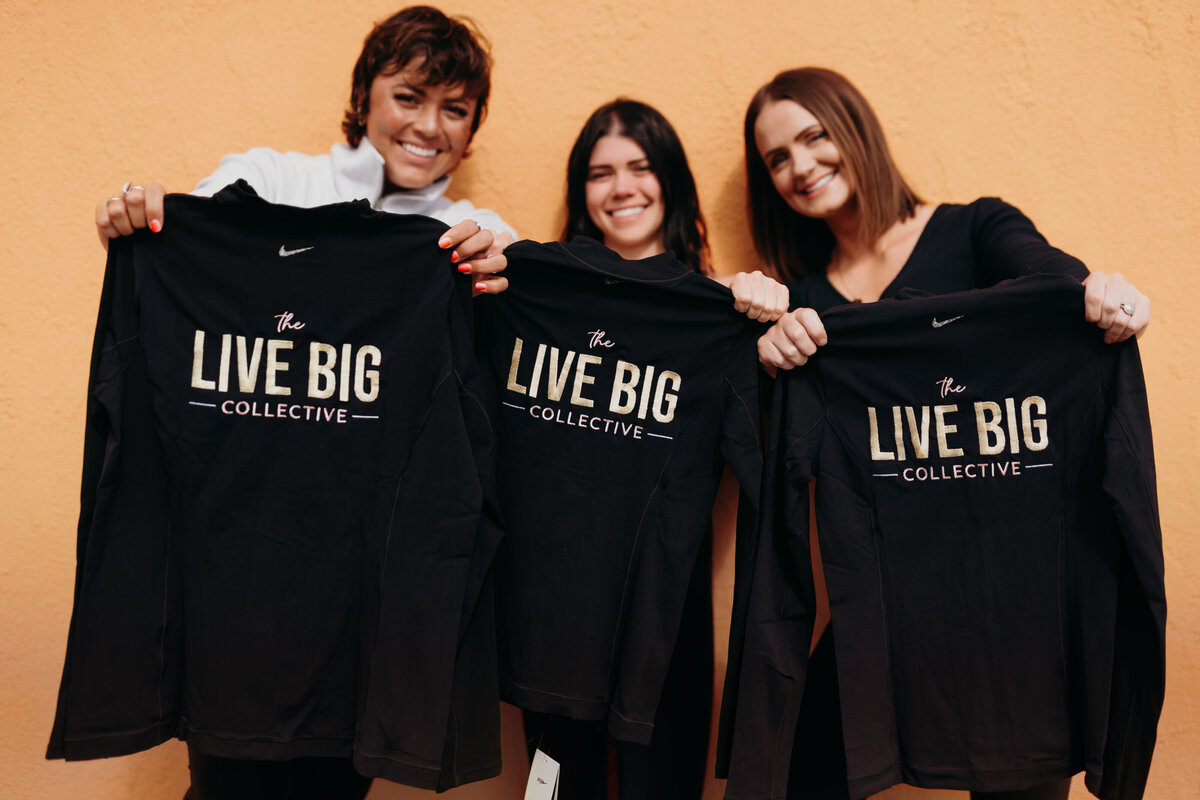 LIVE BIG Coaches holding up LIVE BIG Merch that says "The LIVE BIG Collective" on it