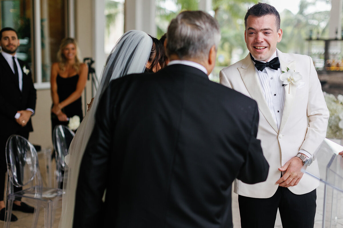 The father of the bride lovingly walking her down the aisle during their Ocean Reef wedding in Key Largo, captured by Claudia Amalia Photography.
