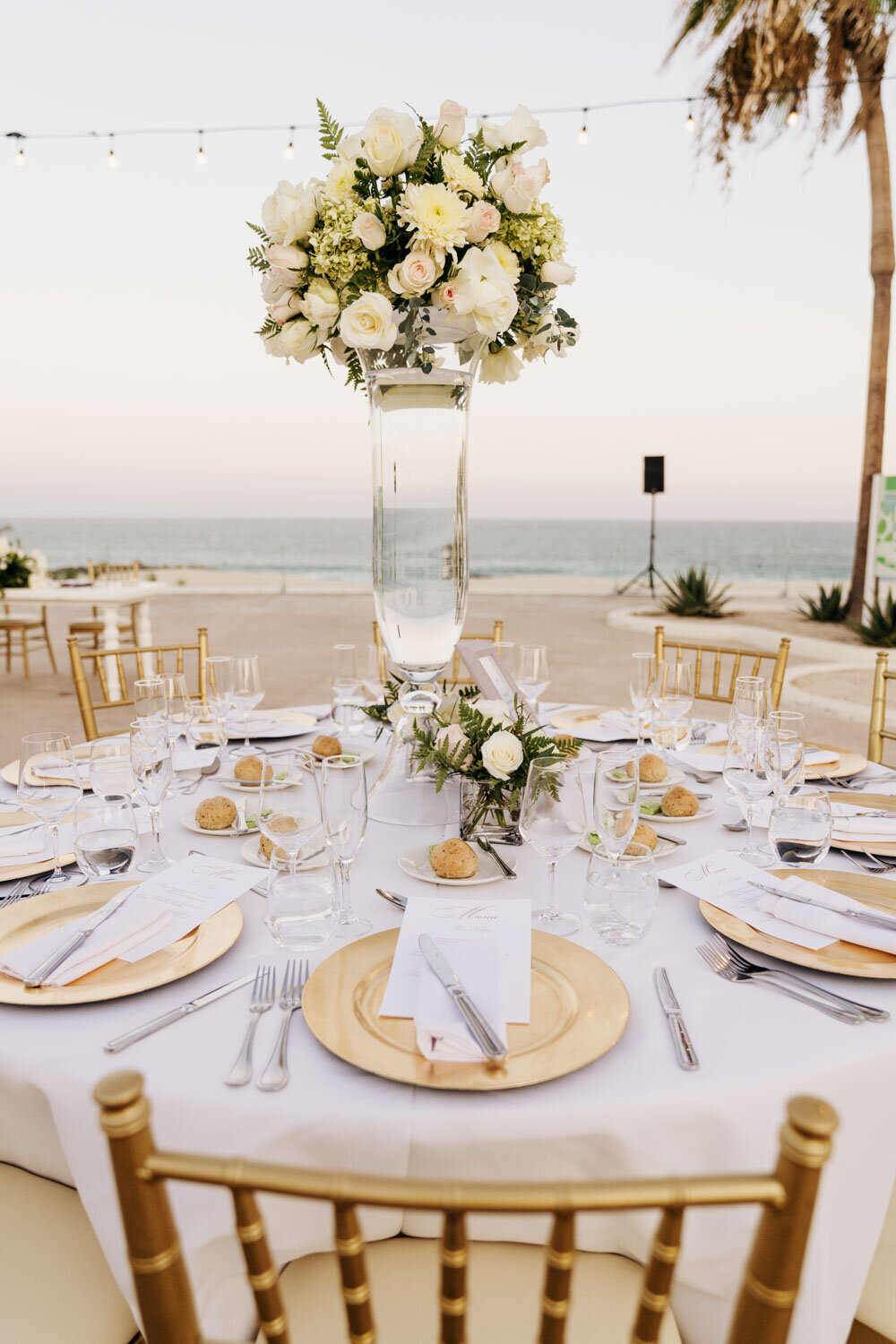Outdoor wedding reception table with floral centerpiece by the ocean