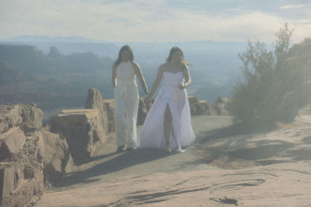 A couple holding hands and walking along a canyon overlook.