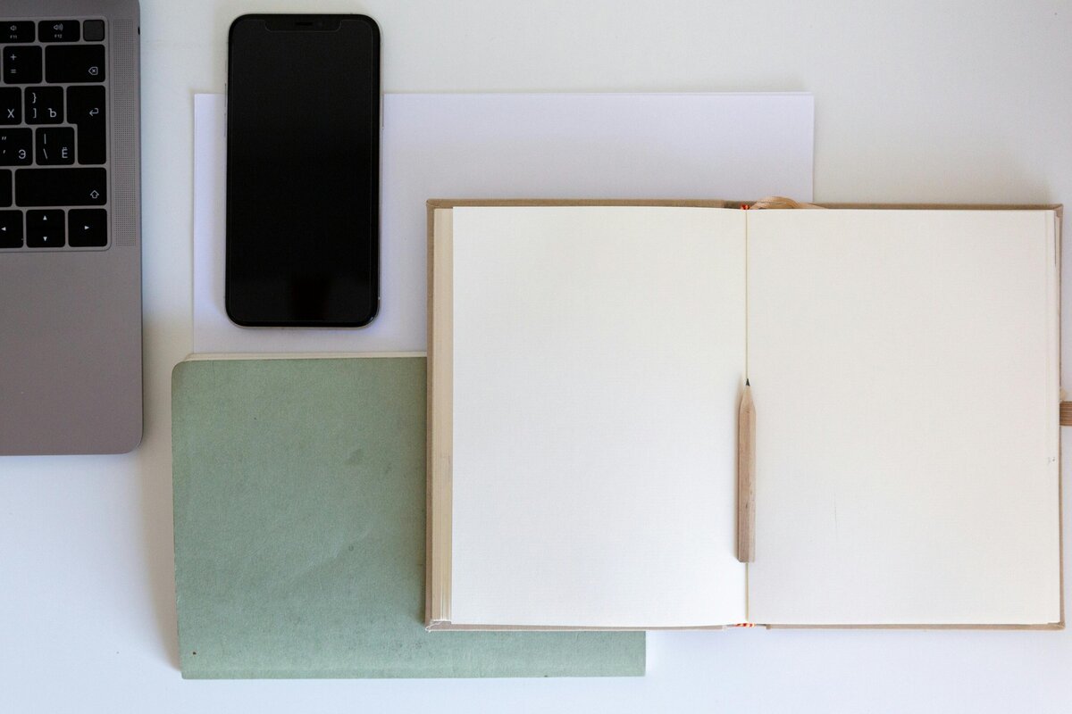 Close-up of notebooks and a phone spread on desk | Rooted Within parent guidance support for families