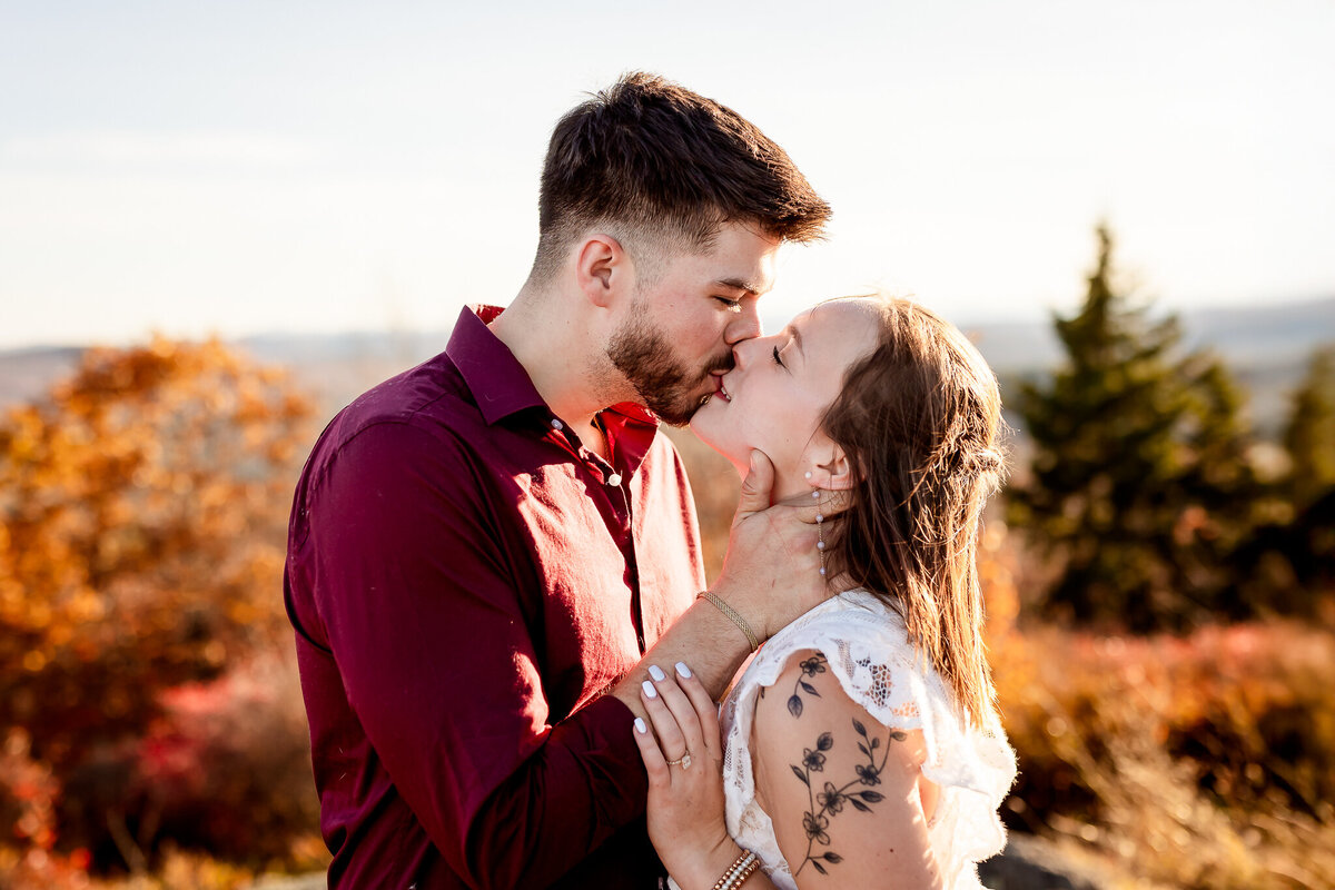 Guy pulling fiancee in and giving her a kiss during fall engagement photography session