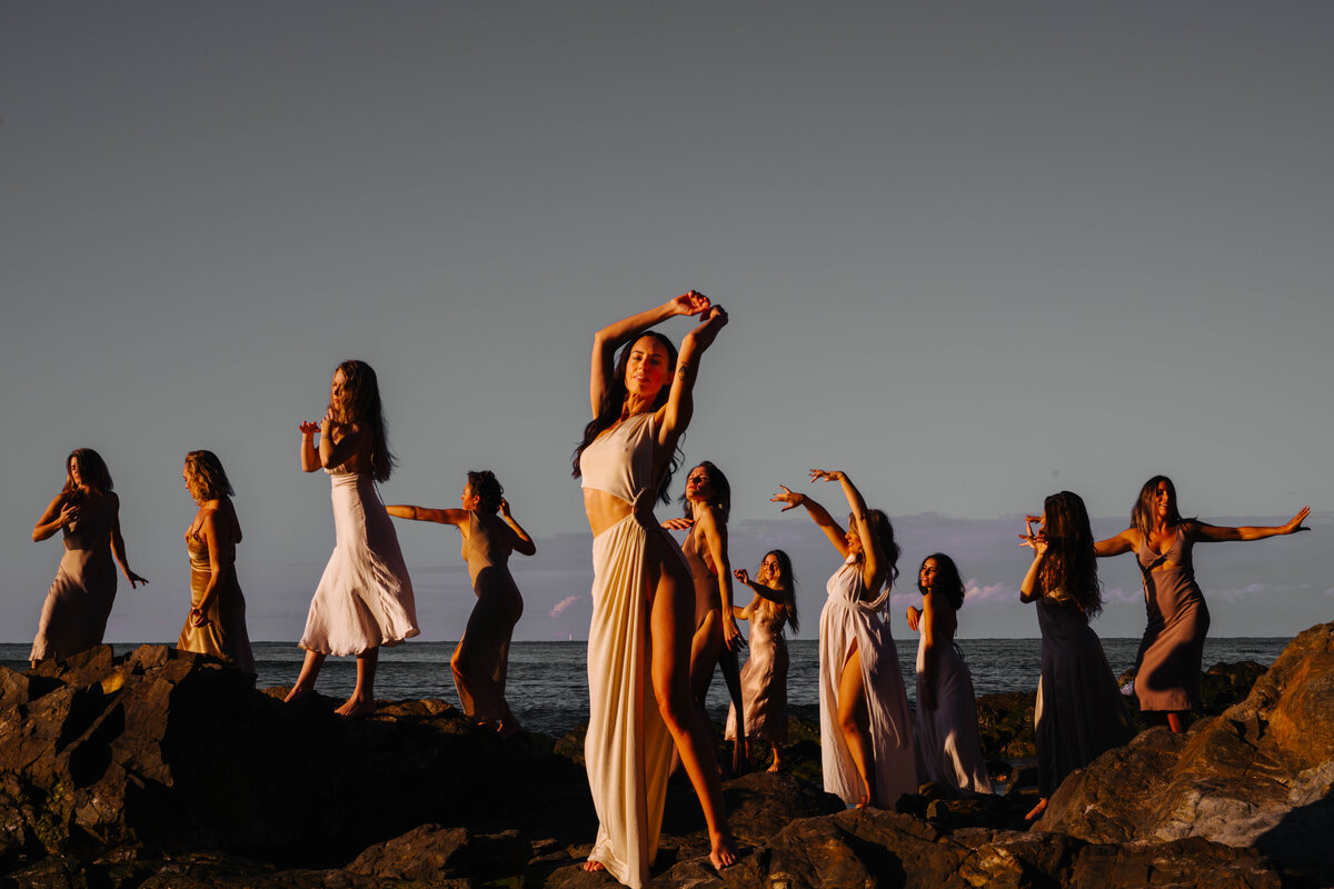 Group of women dancing on rocks by the ocean