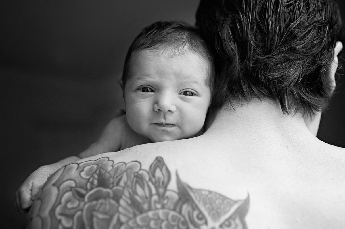 New baby over dads shoulder with tattoo