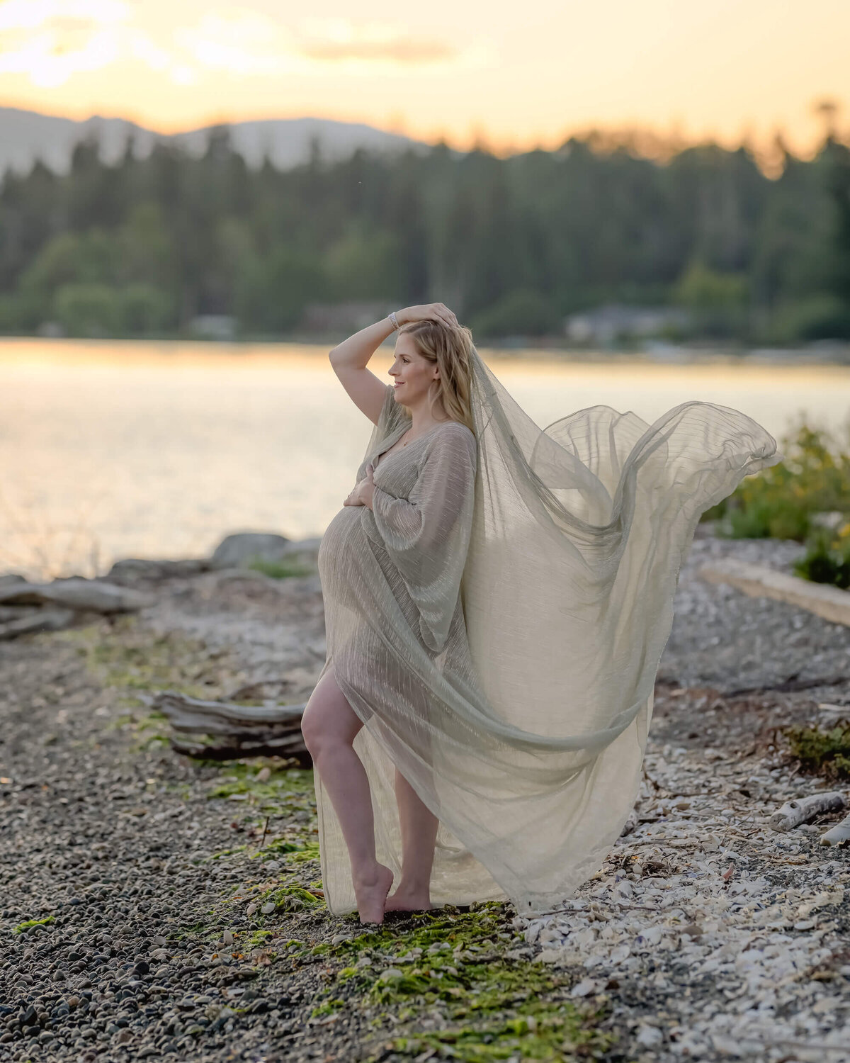 The mom-to-be shines in a sheer golden dress, with a gentle breeze adding movement to the fabric. Image by E. Benecki Photography.