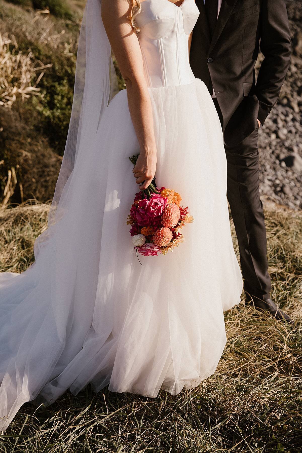 A bride holding bright wedding flowers during a wedding photoshoot with taranaki photographer aimee kelly photography