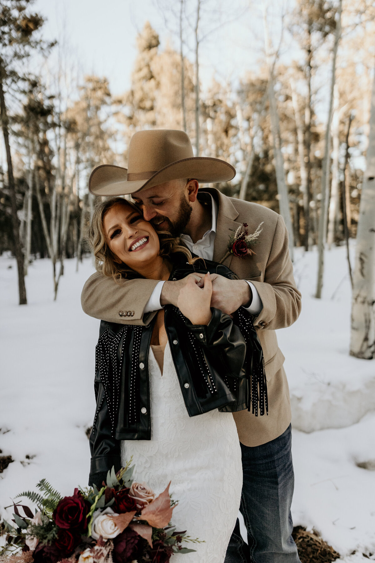 groom holding bride from behind in the snow in Angel Fire, New Mexico