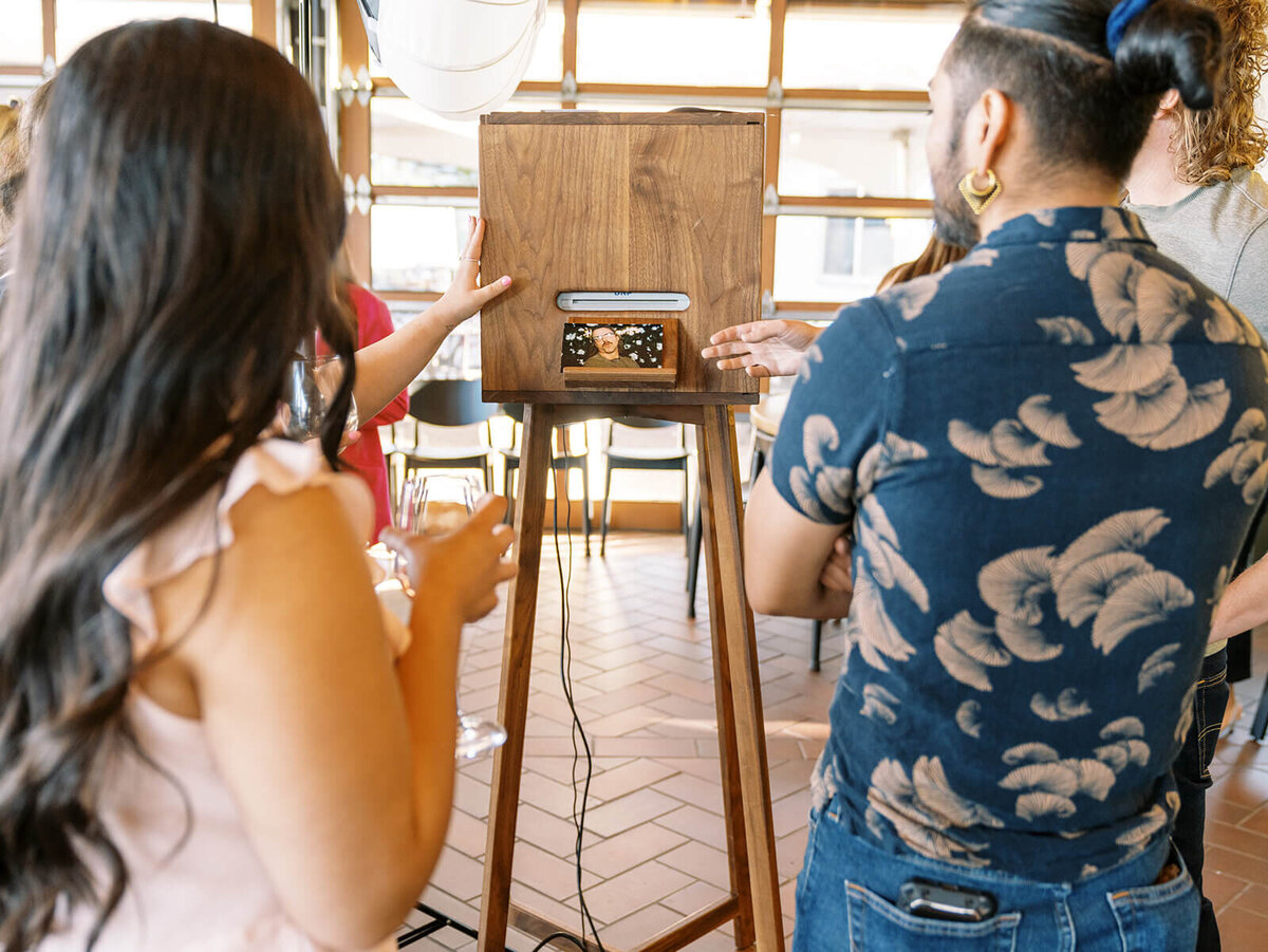 Two people viewing prints on the Birdie Booth, representing the Eugene photo booth's rental options.