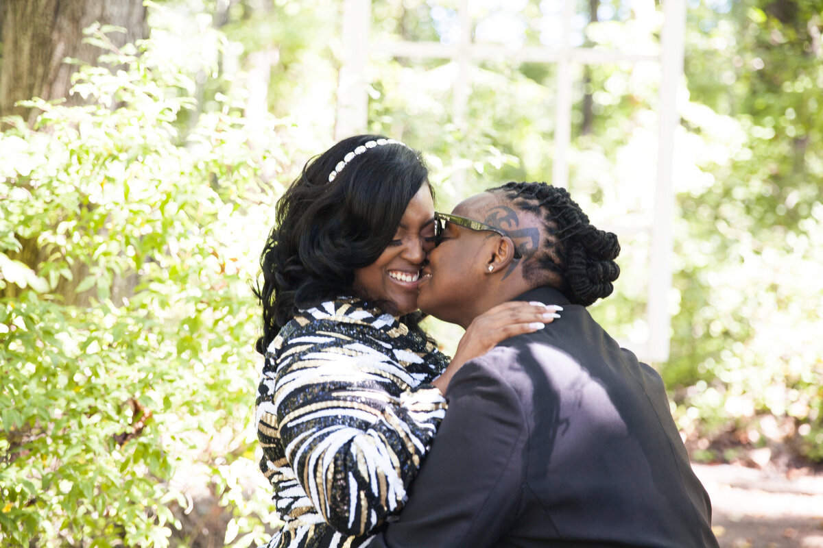 A person kissing their partner on their cheek on their wedding day 