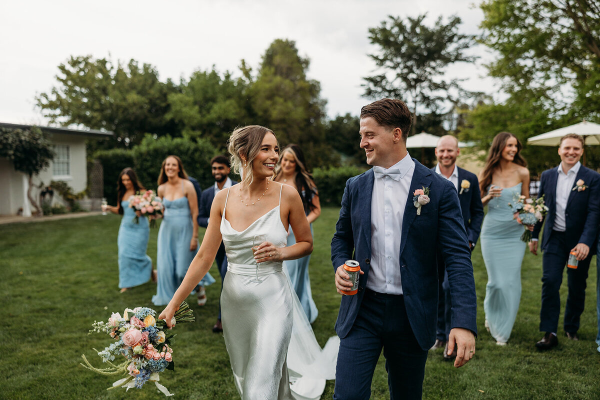 Bride and groom walking with their wedding party behind them
