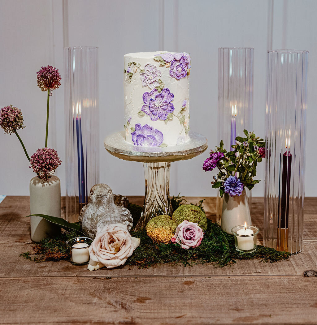 Wedding cake with Fresh Flowers and candles at the reception of a wedding at The Rosewood Venue