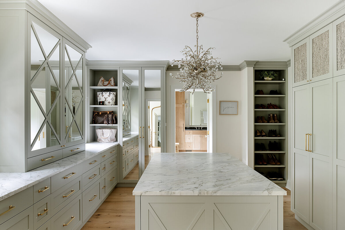 light gray closet room with large marble island and chandelier