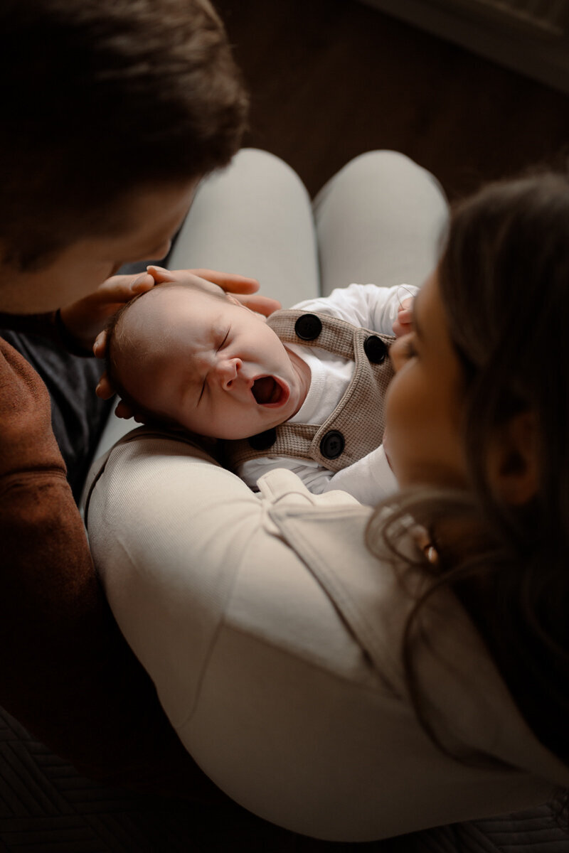 baby gaapt tijdens een newbornshoot terwijl hij bij ouders op schoot ligt