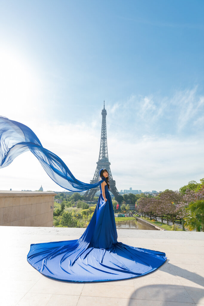 Flying dress photoshoot at Trocadero Paris with Asian woman in flowing blue dress and Eiffel Tower backdrop