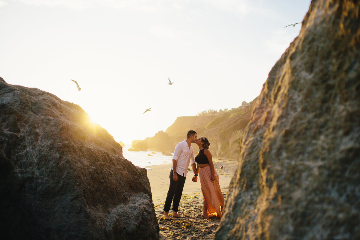 couple kissing in between rocks