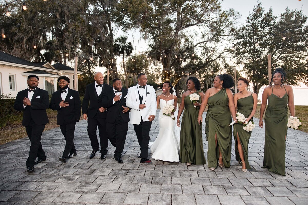 Captured by Phavy Photography, a Jacksonville wedding photographer, this joyful wedding party moment took place at Azaleana Manor in Orange Park. The bride and groom walk hand in hand with their closest friends, dressed in classic black and deep green tones. With a perfect mix of candid energy and luxury style, Phavy Photography delivers elegant, documentary-style wedding photography that feels both timeless and modern.