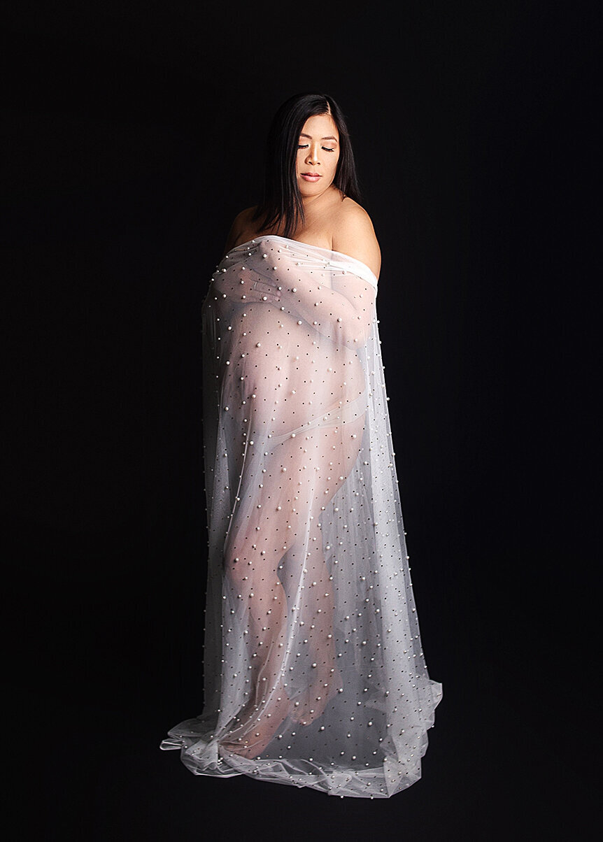 Women with sheer fabric draped over her pregnant belly during maternity photoshoot in Mount Juliet Tennessee photography studio