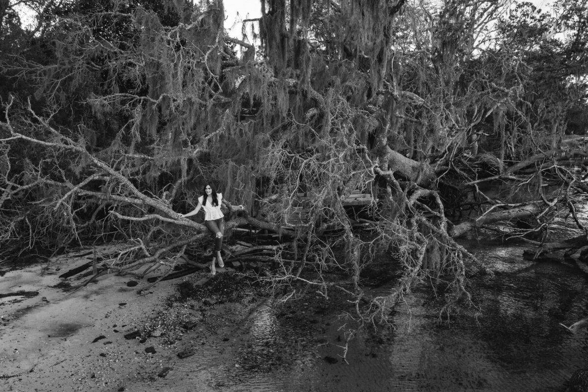 A girl standing along a dead tree