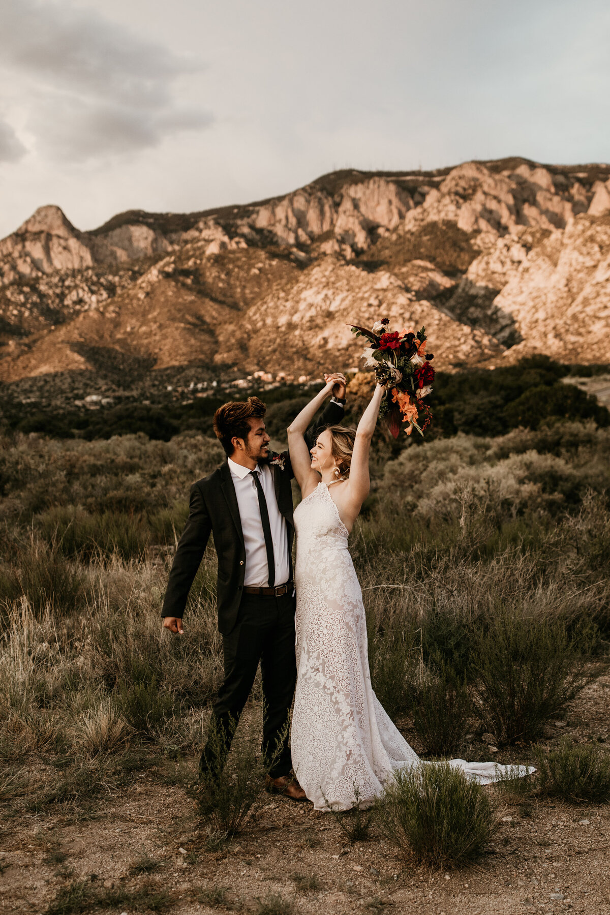 bride and groom celebrating in front of desert mountain