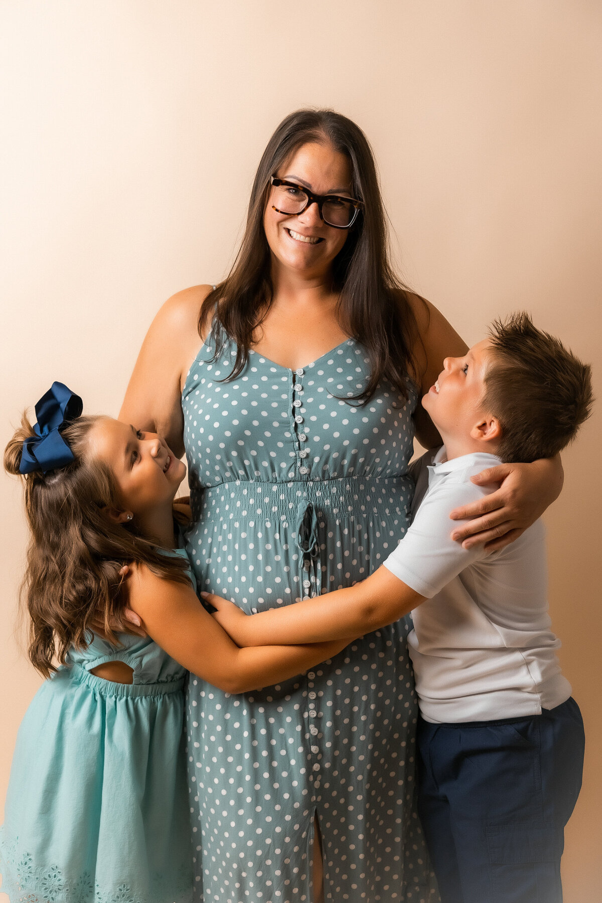 Mom stands in the middle with daughter and son on either side of her smiling at her