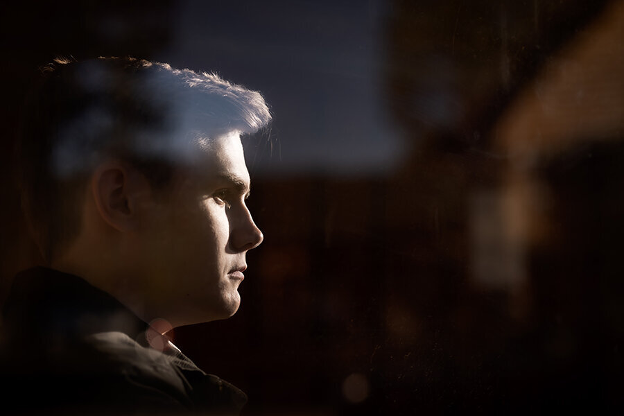 High school senior boy profile viewed through a window.