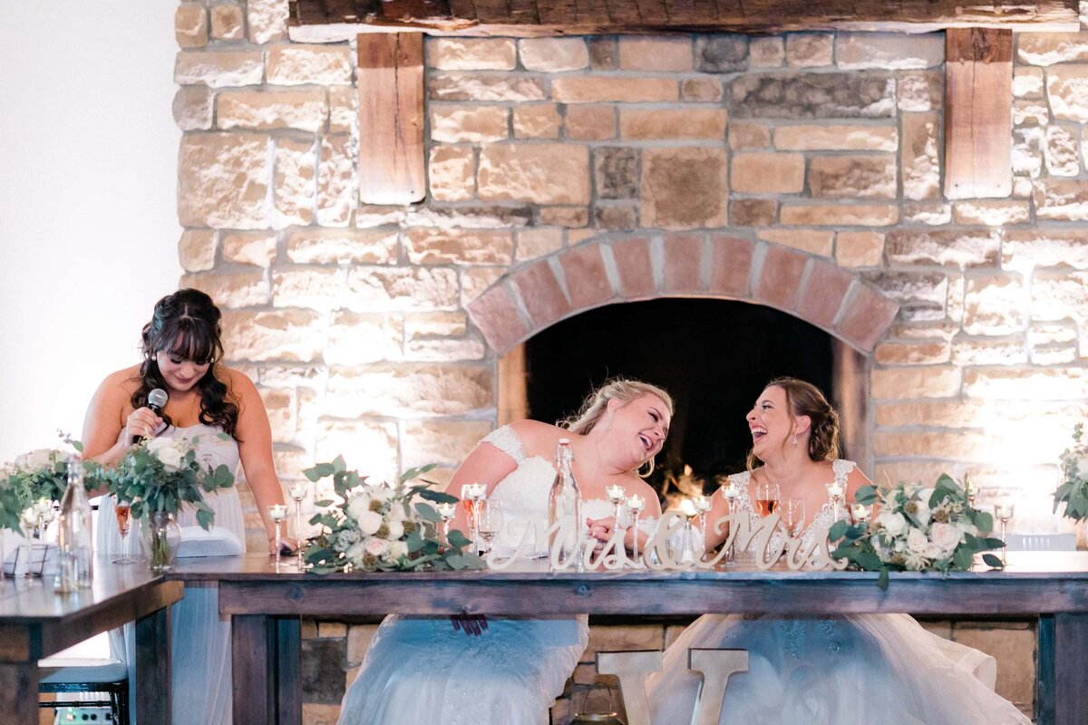 Two brides laughing during toasts
