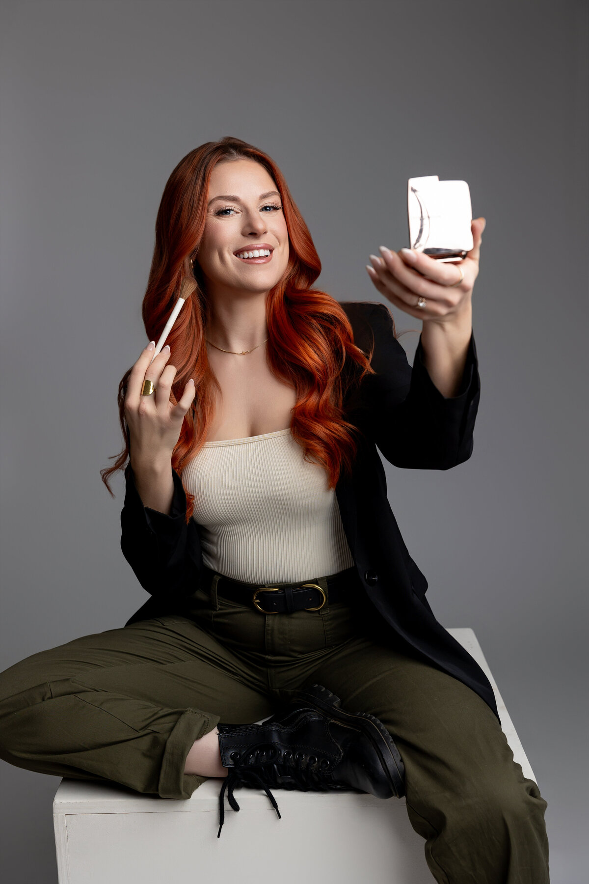 Professional branding portrait of woman with red hair holding compact and brush. Photograph by Yucaipa branding photographer Kaitlyn Dawn Photography.