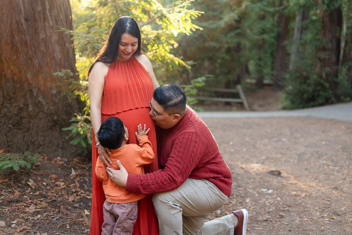 Dad and son kneeling to kiss the baby bump during a maternity session – Ellobelle Photography