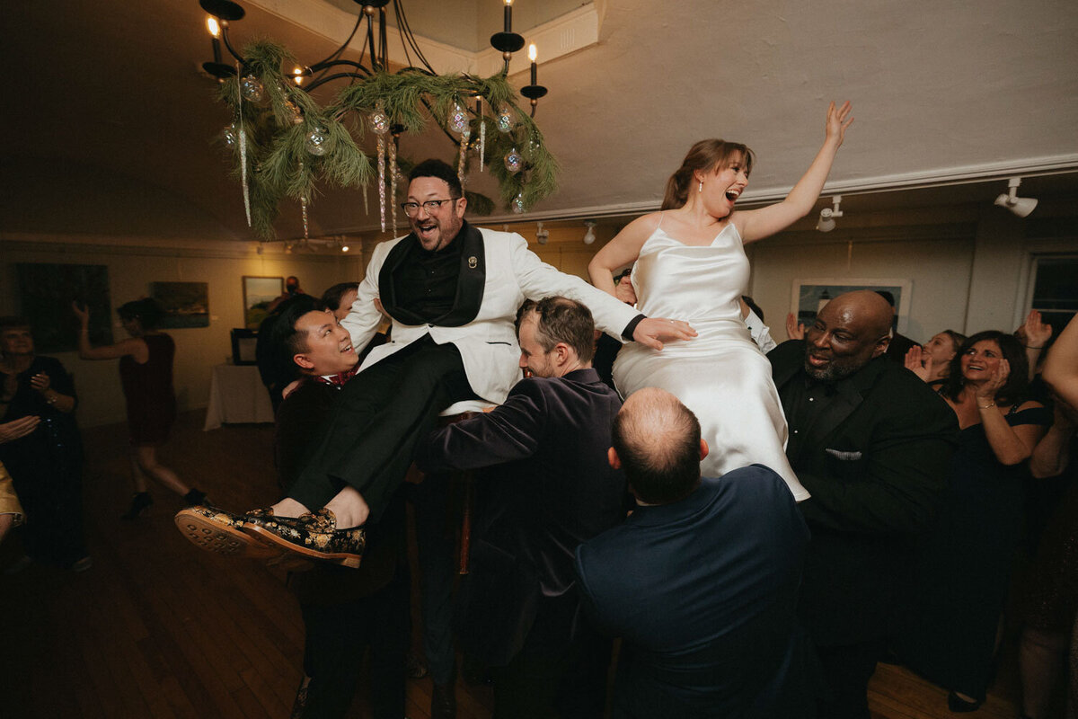 Bride and groom lifted by friends at a wedding reception
