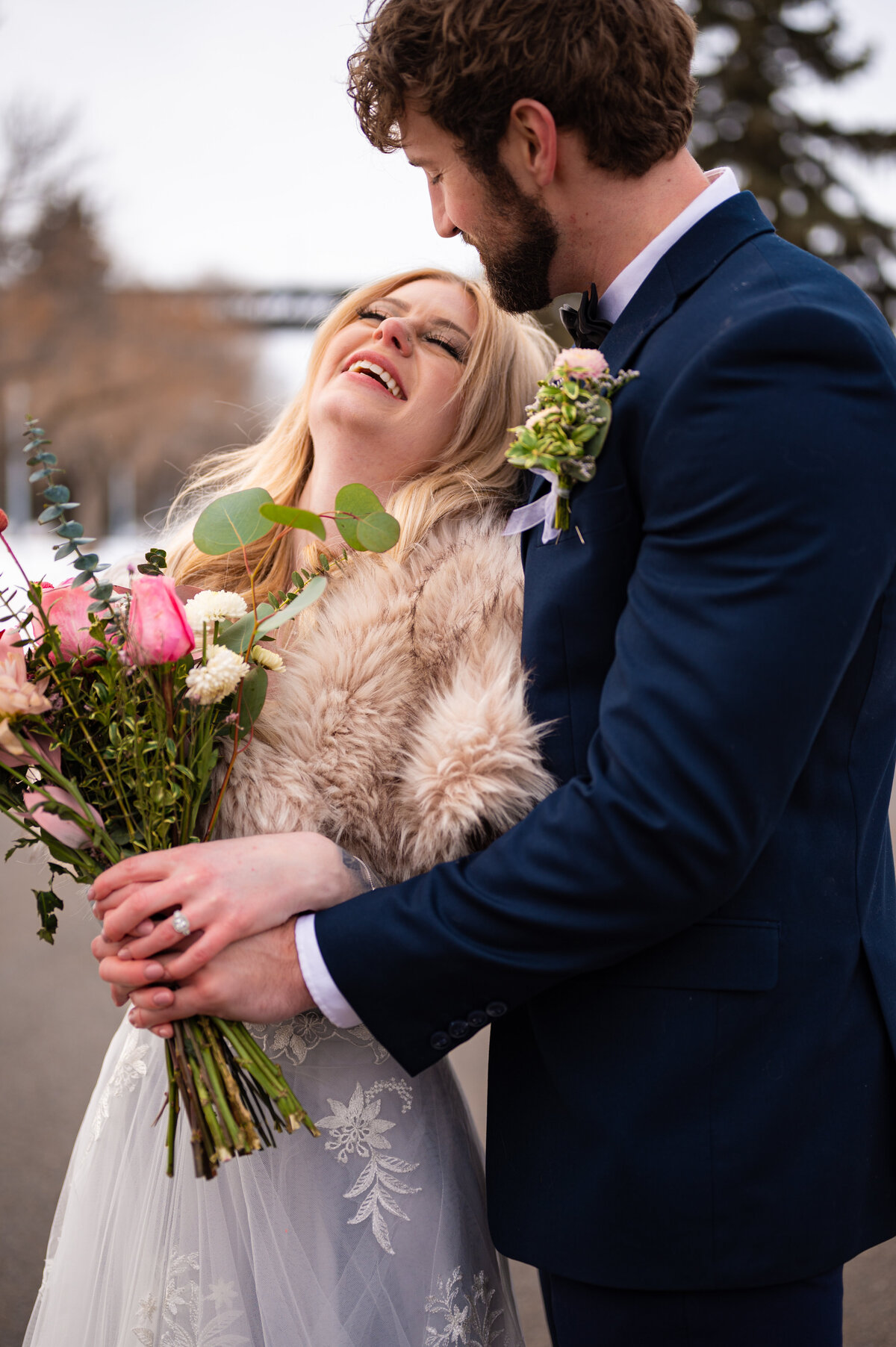 groom whispering  compliments in his brides ear, while bride laughs and smiles