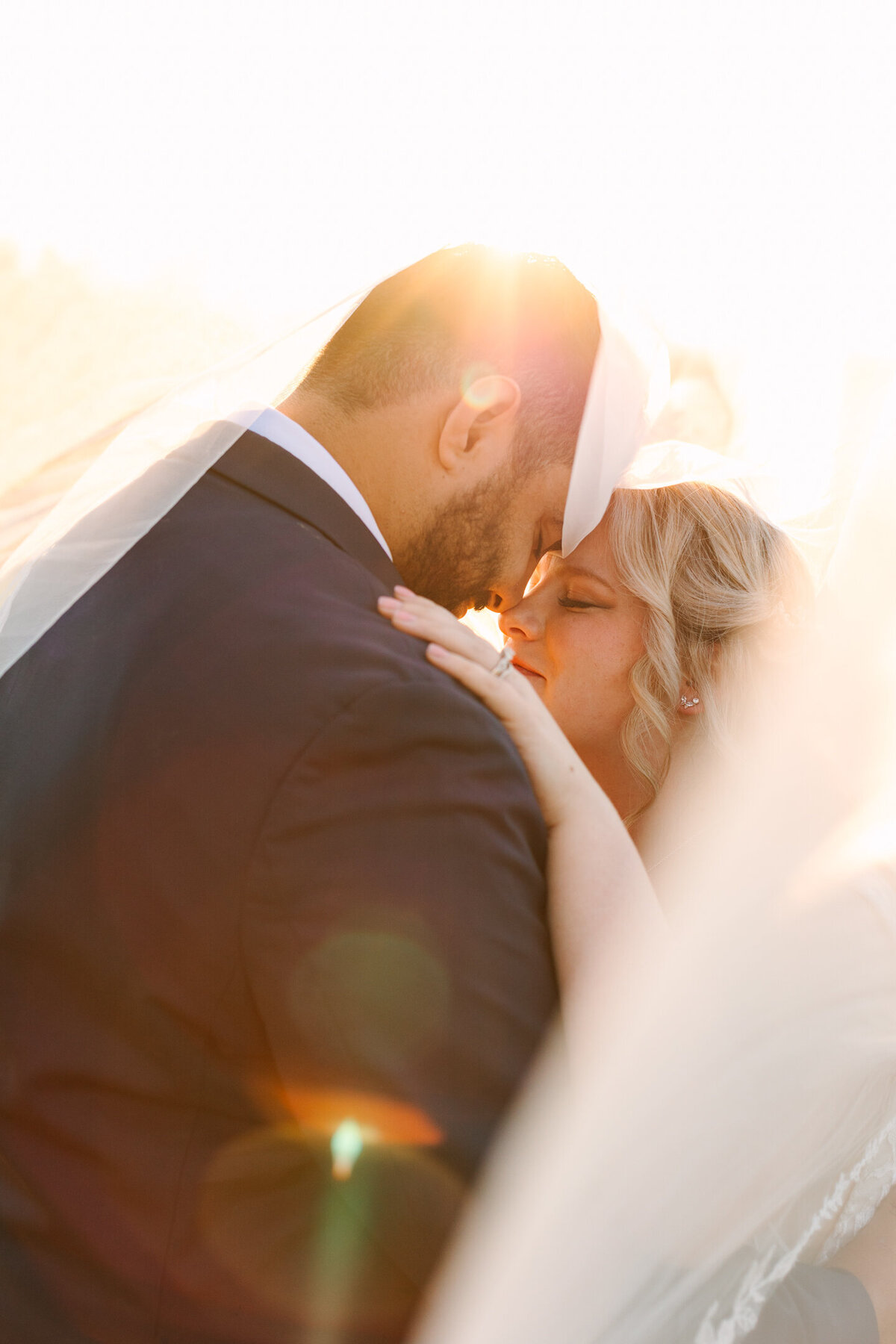 Dramatic veil shot of bride and groom with amazing golden hour light on their wedding day