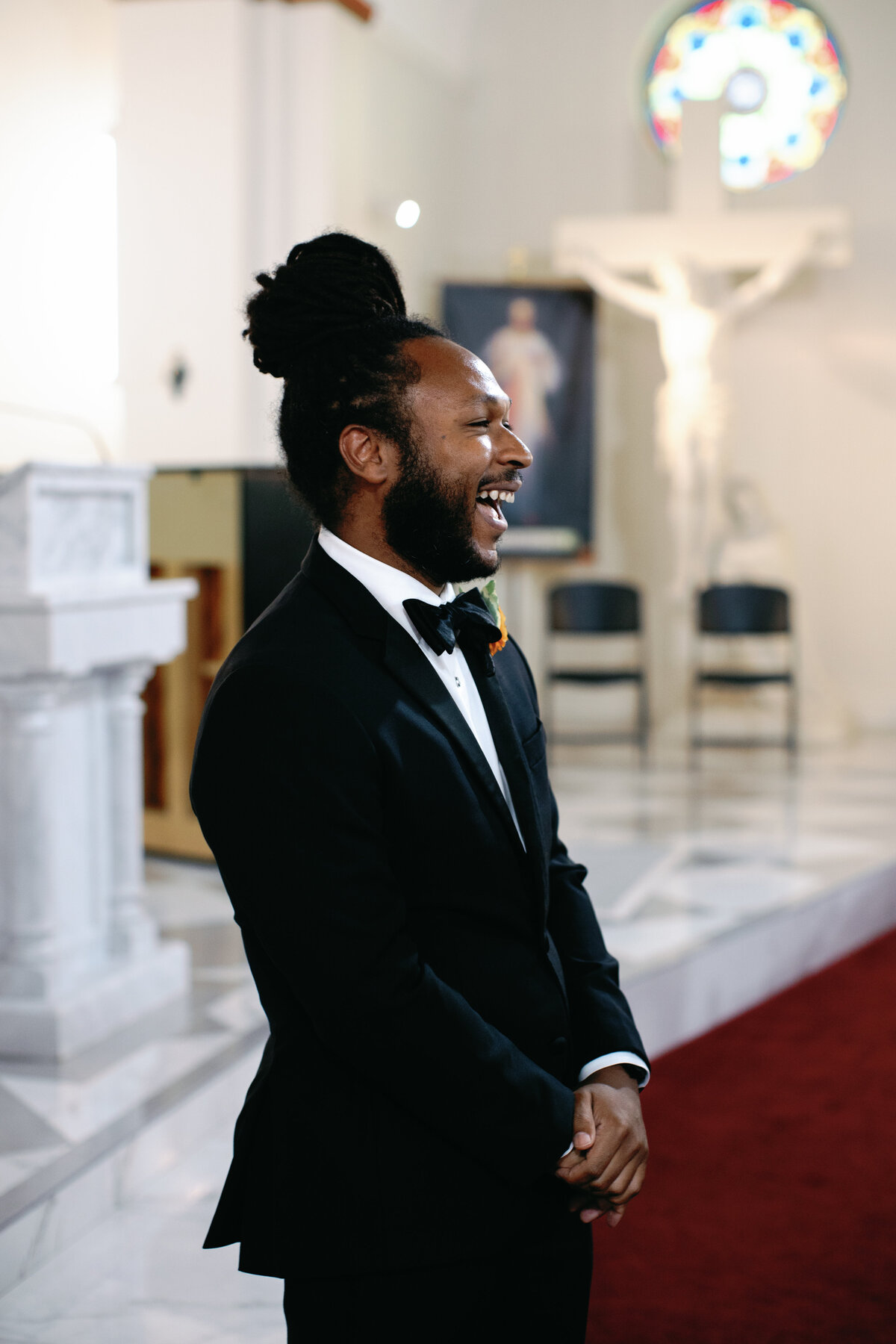 Groom smiling while standing at altar awaiting bride during Catholic wedding in Washington DC.