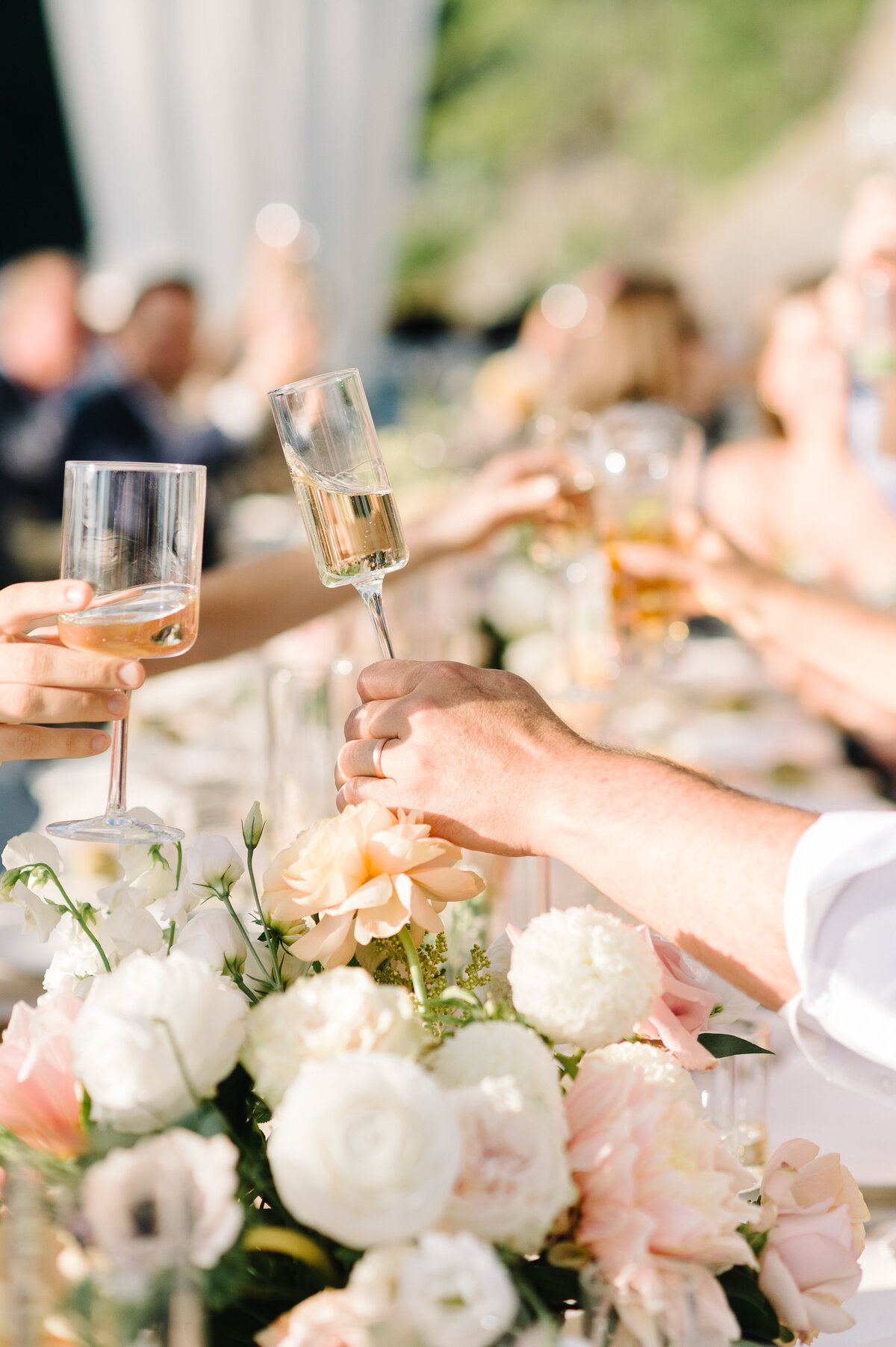 A table of guests cheers their champagne during a tented wedding reception