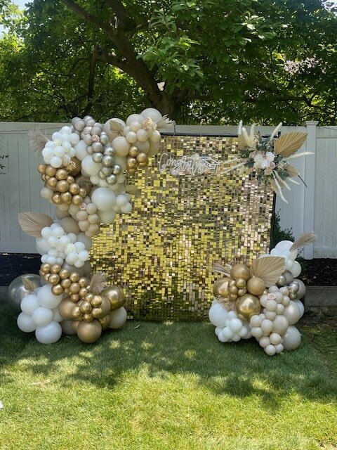 gold shimmer wall with gold and white balloons