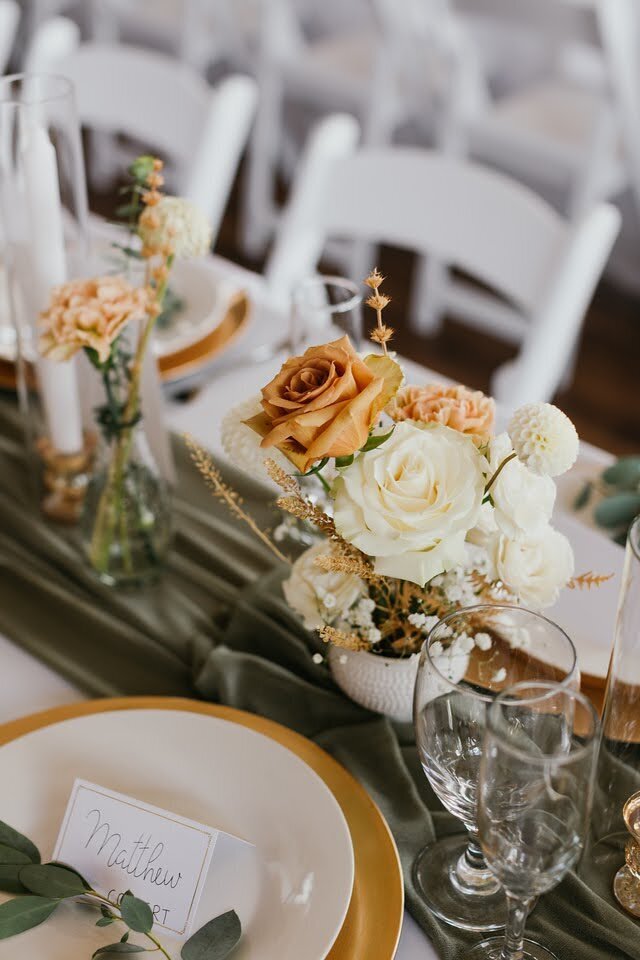 Close up of bud vase floral arrangements by Flowers and Thyme at an indoor wedding reception.