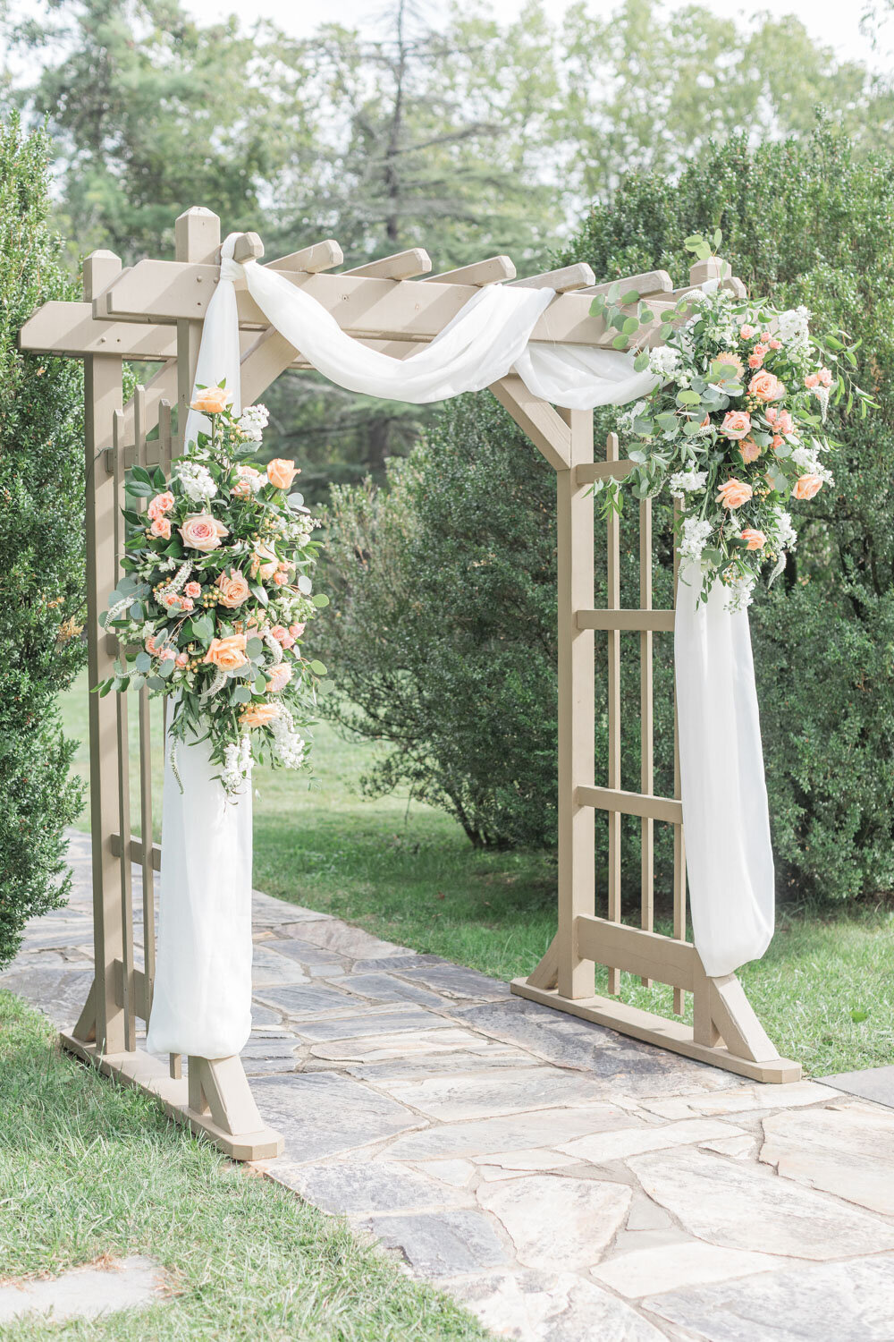 Outdoor wedding altar design with wooden arch, white cloth and flowers