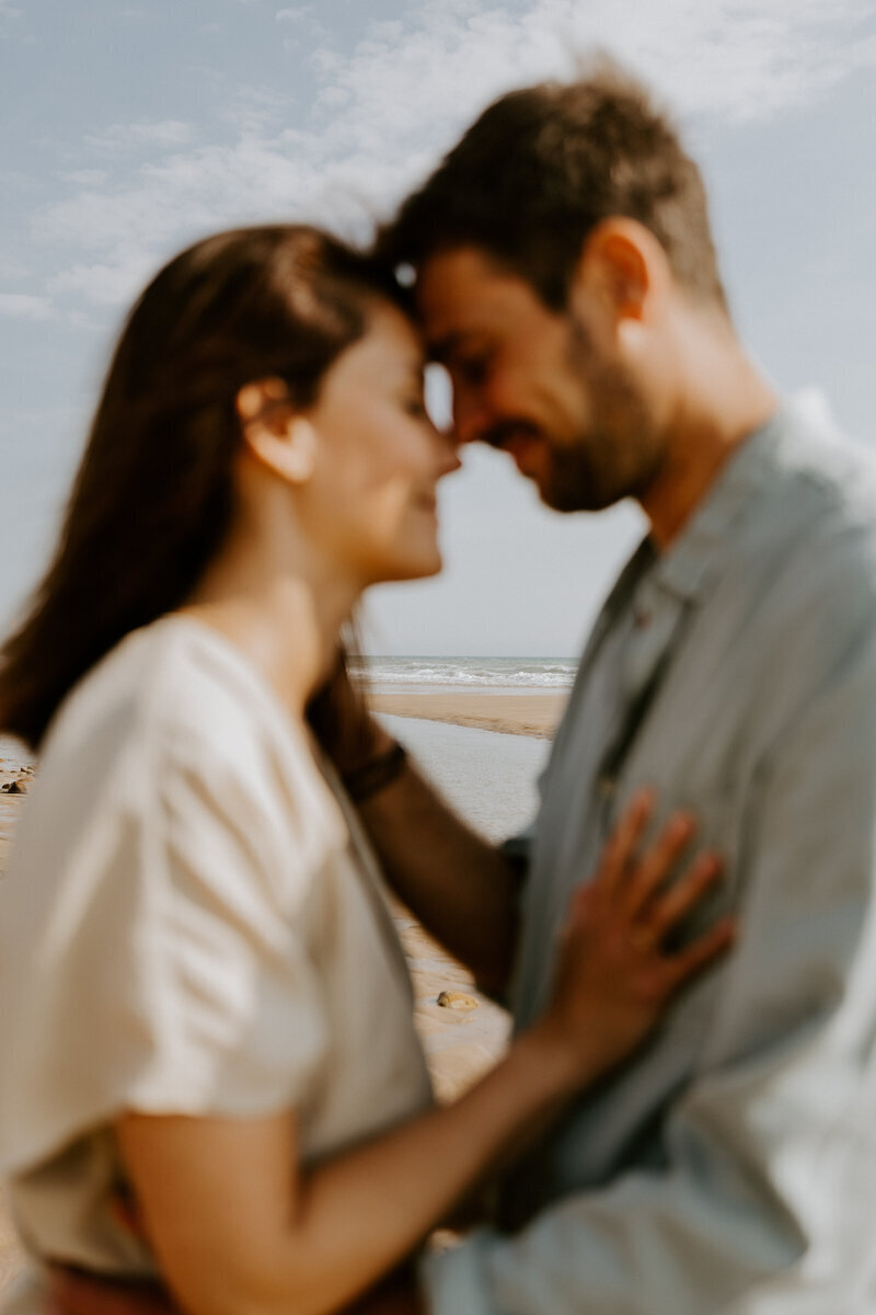 Couple se faisant face, effet de flou. Plage en arrière plan. Séance photo en Vendée.