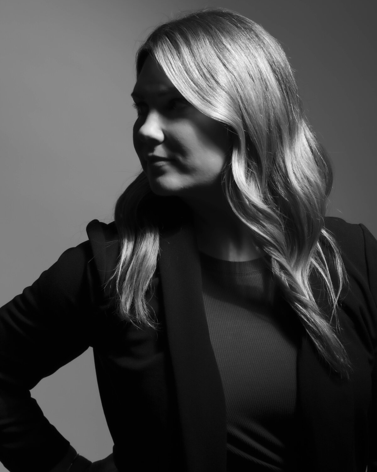 Black-and-white headshot in CT of blonde woman in dark blazer, side-lit for a bold, artistic portrait by Rob Faber Photography.