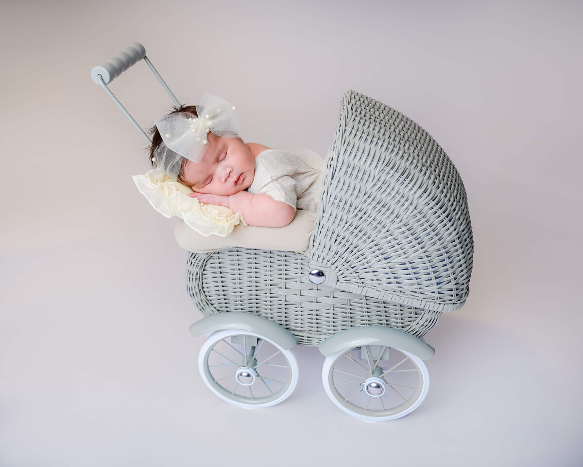 Kitsap county, WA newborn photoshoot of a sleeping baby posed in a small gray stroller. Image by Beth Benecki.