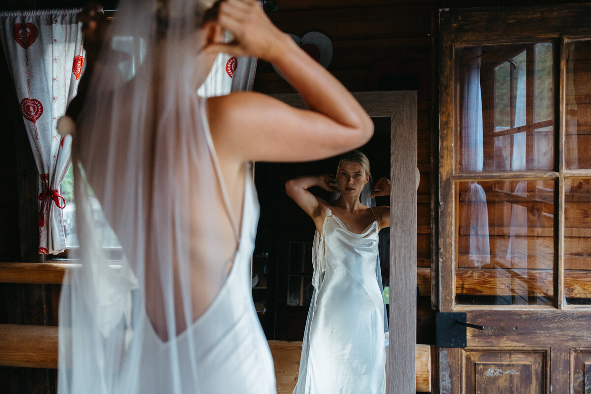 Bride adjusting veil near rustic wooden doorway
