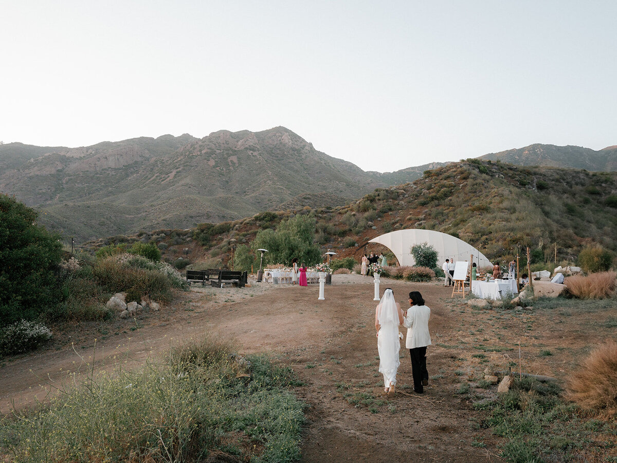 Bride and groom walking through a scenic outdoor wedding venue in the mountains of Malibu, captured in a candid, documentary style by Chicago wedding photographer Abe Fernandez
