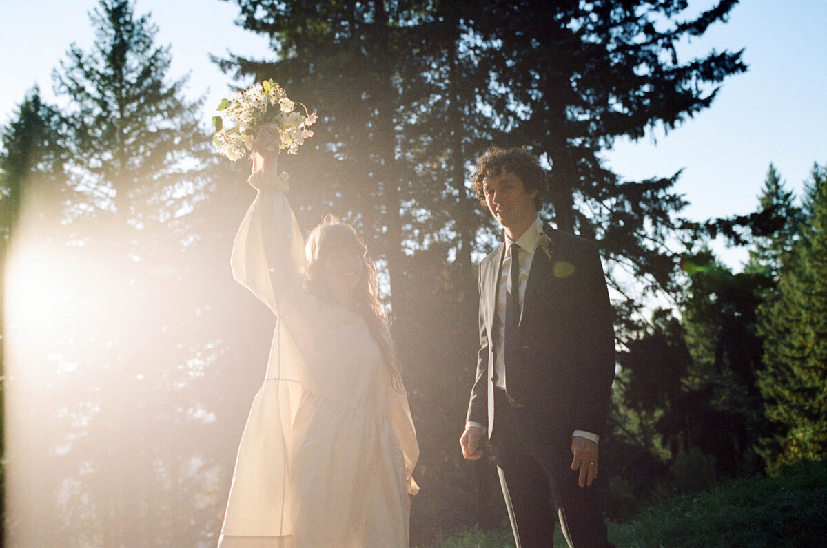 Bride and groom illuminated by the sun, looking at the camera at the top of Mt. Tabor in Portland.